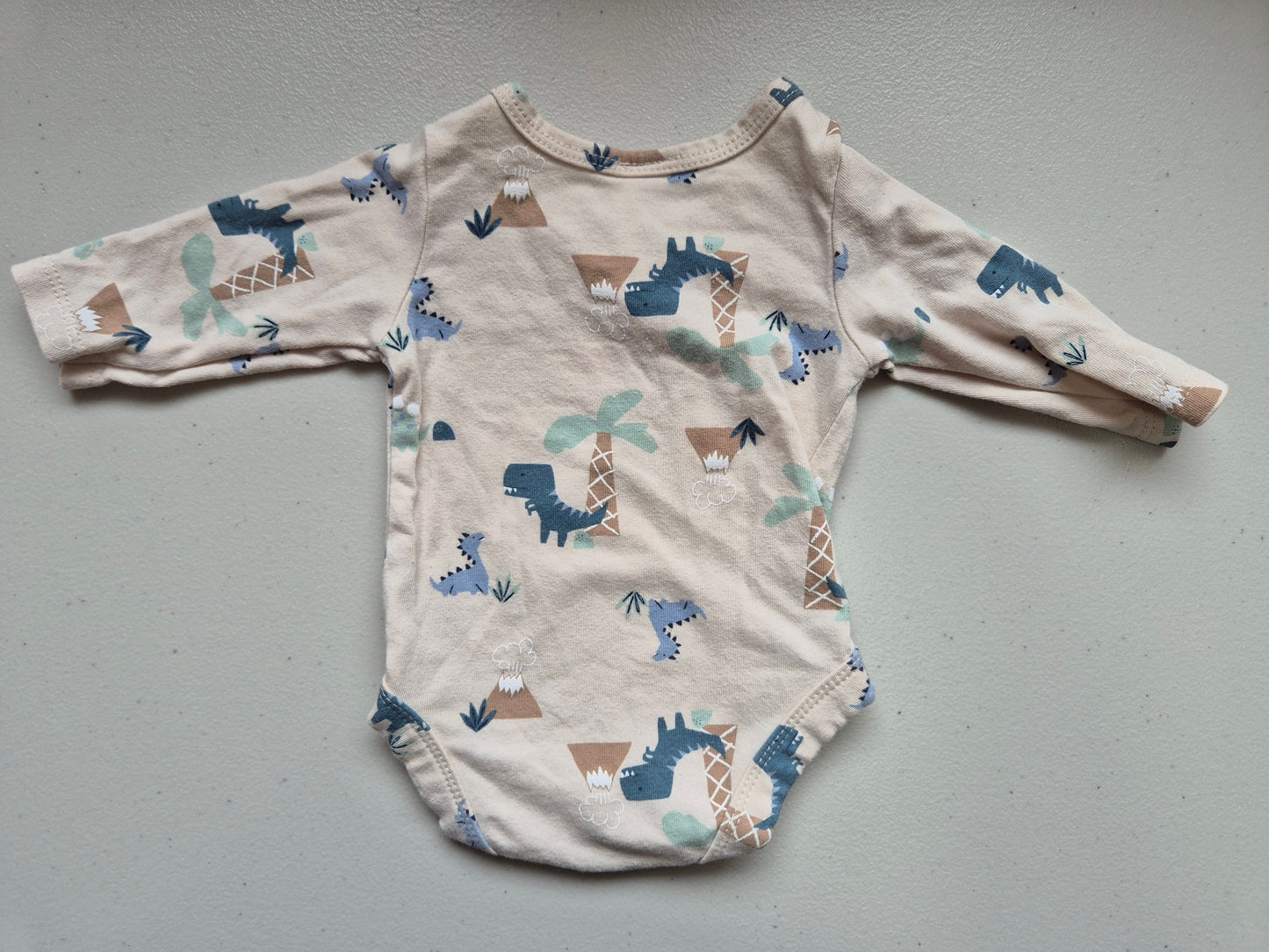 Baby onesie with animal pattern on a gray surface
